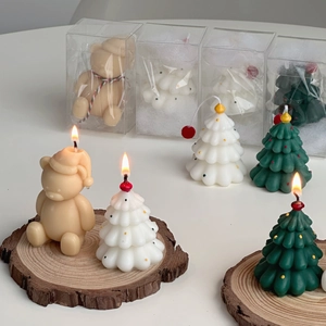 Detail of Christmas tree and bear shaped candles in elegant transparent gift box