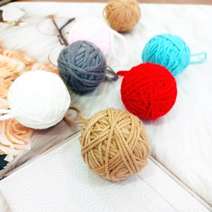 Close-up of colorful handmade wool felt balls with roses and glasses on a plush white rug