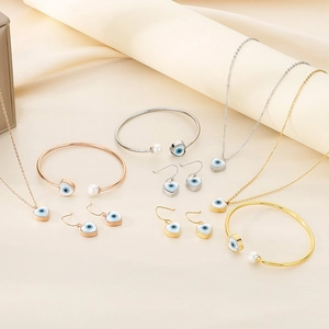 Three-piece jewelry set with evil eye heart pendant and pearl bangle in three metal colors