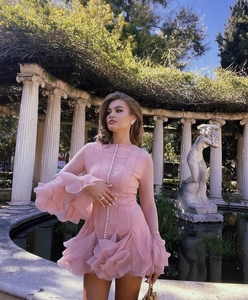 Detail of pink tiered chiffon dress with pearl buttons against classic stone garden