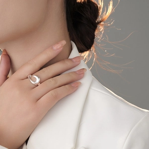 Macro detail of irregular liquid silver ring on model finger with high mirror finish