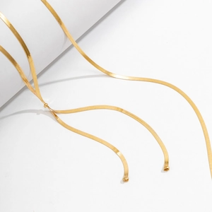 Detailaufnahme einer goldenen Schlangenkette auf weißem Sockel mit feiner Textur