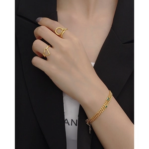 Luxurious gold chain bracelet with emerald green stones and geometric rings set