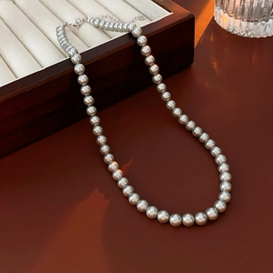 Detail of grey metallic pearl necklace with lobster clasp on vintage jewelry box display