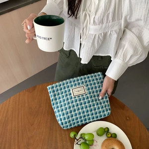 Détail d'une pochette tissée à carreaux bleus et blancs avec étiquette Pleasant Time sur table