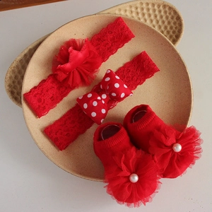 Detail view of red baby headband set with lace crown and pearls on knit socks