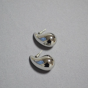 Detail view of high-polished silver water drop earrings with a reflective metallic finish