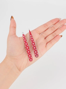 Detailed view of red polka dot slanted and pointed tip tweezers held in hand