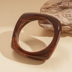 Close-up of a thick square amber resin bangle with tortoise shell pattern on stone