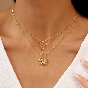 Détail de colliers dorés superposés avec pendentifs nœuds et chaîne serpent en gros plan