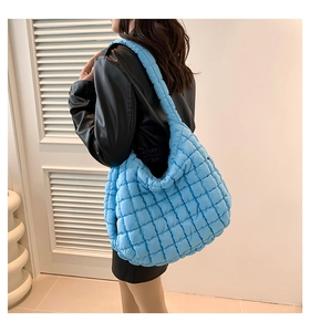 Detail view of a bright blue quilted crossbody cloud bag in large size with cotton padding