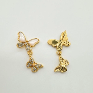 Détails macro des boucles d'oreilles papillon en or 18 carats avec nacre et zircons