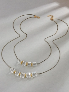 Primer plano de cuentas de cristal transparente y anillos dorados en un collar largo
