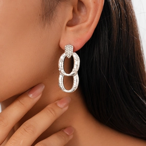 Close-up of geometric silver earrings with hammered texture and pave cubic zirconia