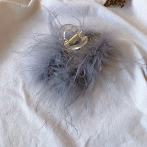 Detail shot of grey ostrich feathers on transparent hair claw clip with golden spring