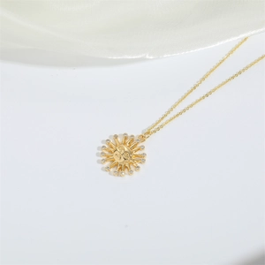 Close-up of gold sun smiley pendant necklace with sparkling crystals on white silk