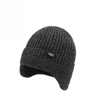 Detail of dark grey knit beanie with sport tag, ribbed texture and ear protection flaps