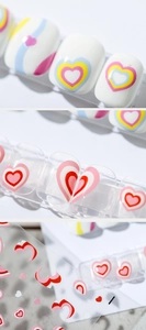 Macro detail of 5D heart-shaped nail art stickers with various colorful pattern designs