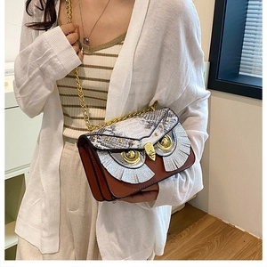 Détail du sac bandoulière hibou avec des yeux dorés et des textures de cuir mélangées