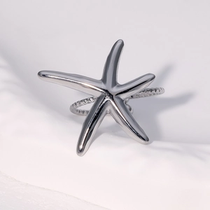 Macro shot of a silver starfish ring with a textured diamond-cut band on a white base