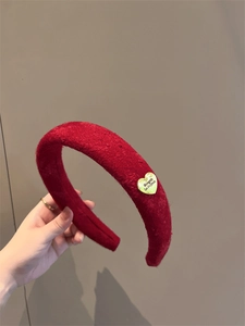 Detail of red velvet headband with golden heart-shaped metal tag and engraved French script