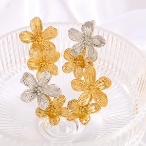 Elegant 18K gold and silver floral tassel earrings set inside a ribbed glass bowl