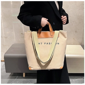 Detail of beige canvas tote with brown leather handles and HT FASI N logo print