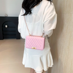 Close-up of pink quilted leather bag with gold metal lock and chain strap on a dress