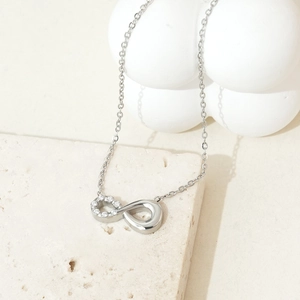 Macro shot of silver infinity pendant necklace with zircon crystals on marble surface