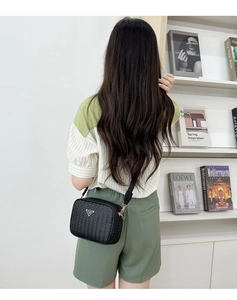 Detail of woven texture cross-body camera bag with triangle logo and wide nylon strap
