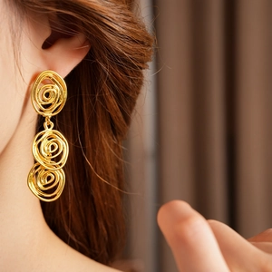 Detail view of vintage golden triple spiral flower earrings on model with retro style