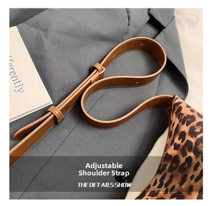 Close-up of the adjustable brown leather strap and stitching on the leopard print bag
