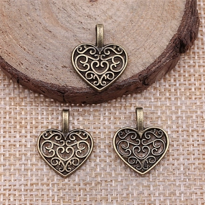 Three vintage heart filigree pendants on rustic wood for handmade jewelry crafts
