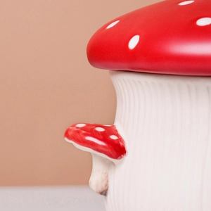 Close-up of red and white spotted ceramic mushroom jar with lid and small side accents