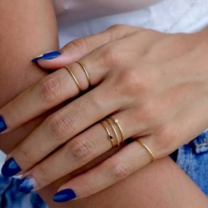Detailed view of layered 18K gold plated birthstone rings on model with denim background