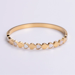 Detail of gold heart bangle with white mother-of-pearl inlays for a sleek minimalist look