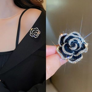 Detailed view of a vintage black rose brooch with silver metal base and inlaid rhinestones