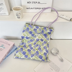 Dettaglio borsa tote in tela a fiori con spalline viola e oggetti di scena in stile retrò