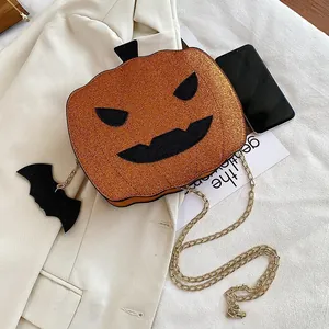 Close-up of orange sequin pumpkin crossbody bag with gold chain and bat charm