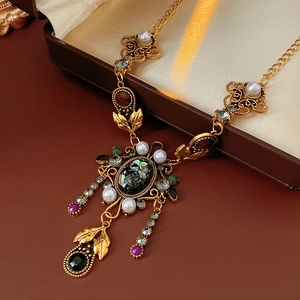 Détail d'un collier vintage doré avec cristaux colorés et perles sur boîte à bijoux