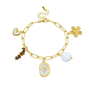 Detailed view of gold chain bracelet with baroque pearl, heart, and flower charms