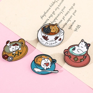 Four cute enamel cat coffee cup pins arranged on decorative stationery background
