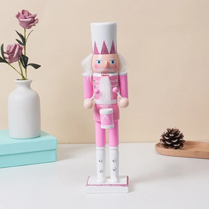 Detail of pink wooden nutcracker drummer with drumsticks on a decorated white tabletop