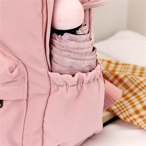 Pink canvas backpack with rabbit ears featuring an elastic side pocket holding a purple umbrella