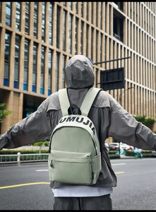 Light green waterproof backpack shown from a rear outdoor view for daily commute