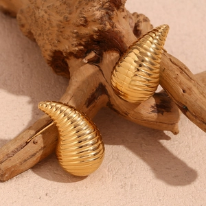 Detailed close-up of gold plated hollow teardrop earrings with textured spiral design
