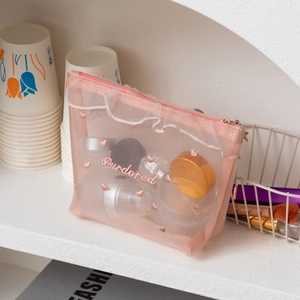 Detailed view of pink mesh makeup bag featuring heart embroidery and delicate lace trim
