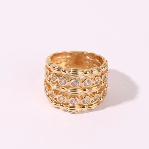 Elegant gold-plated wheat-ear ring with rows of sparkling zircon stones on white backdrop