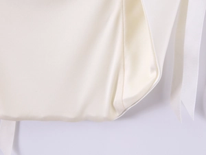 Detailed macro view of off-white satin fabric texture and premium ribbon stitching detail