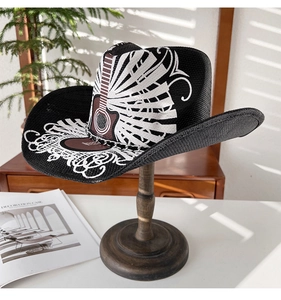 Détail d'un chapeau de cowboy noir tressé avec motifs guitare sur un support en bois